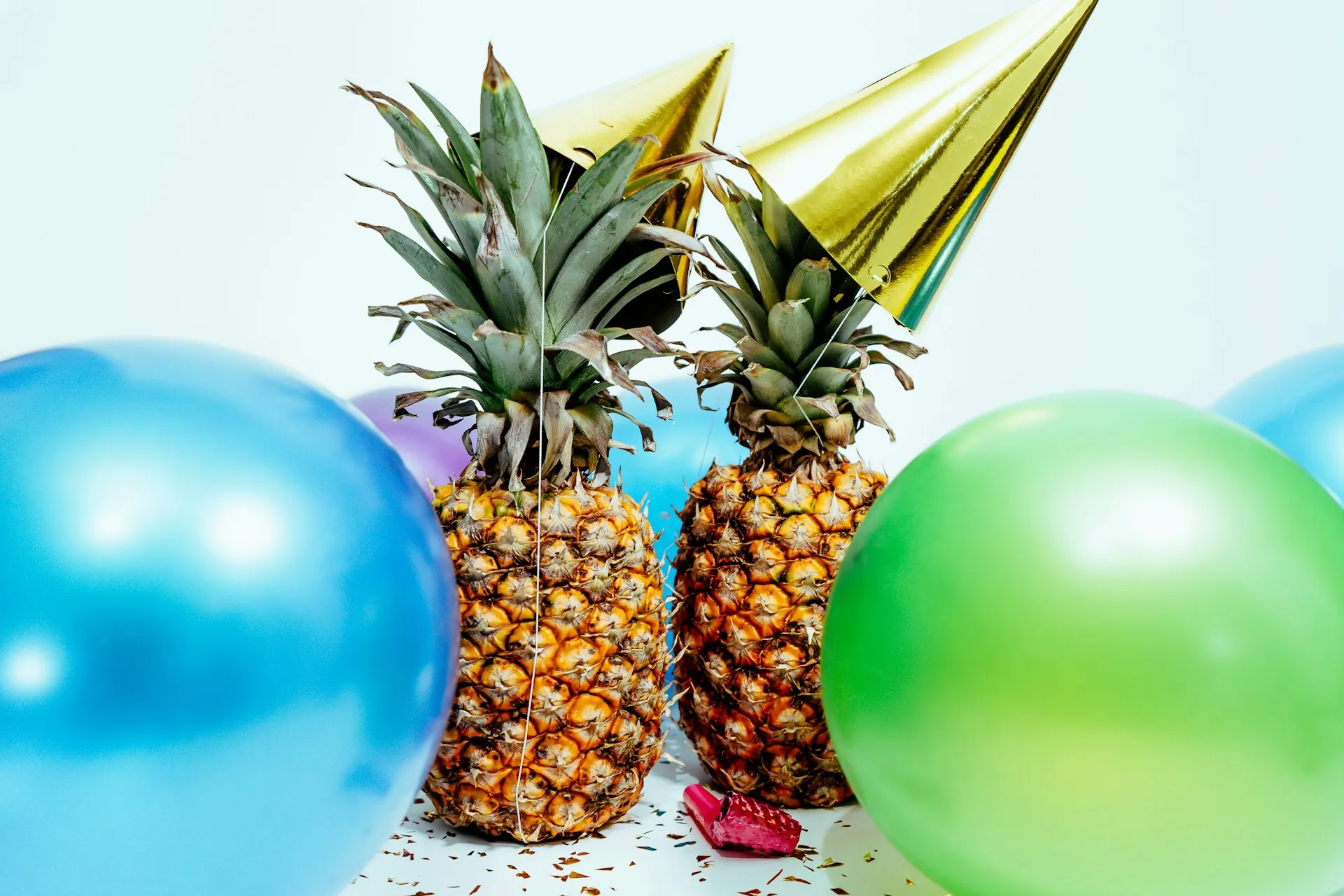Two pineapples sharing a party with hats and balloons, celebrating a job of a Resume Pineapple customer.